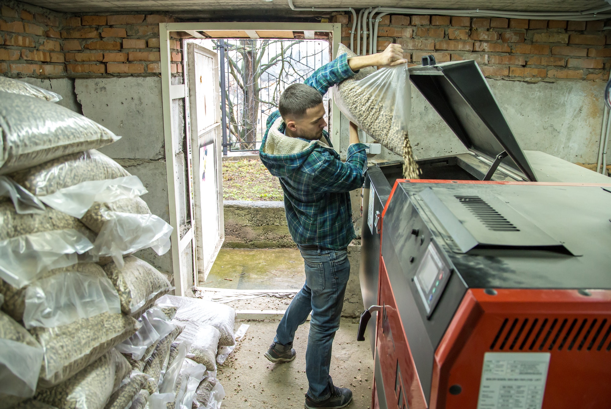 the man loads the pellets in the solid fuel boiler, economical heating
