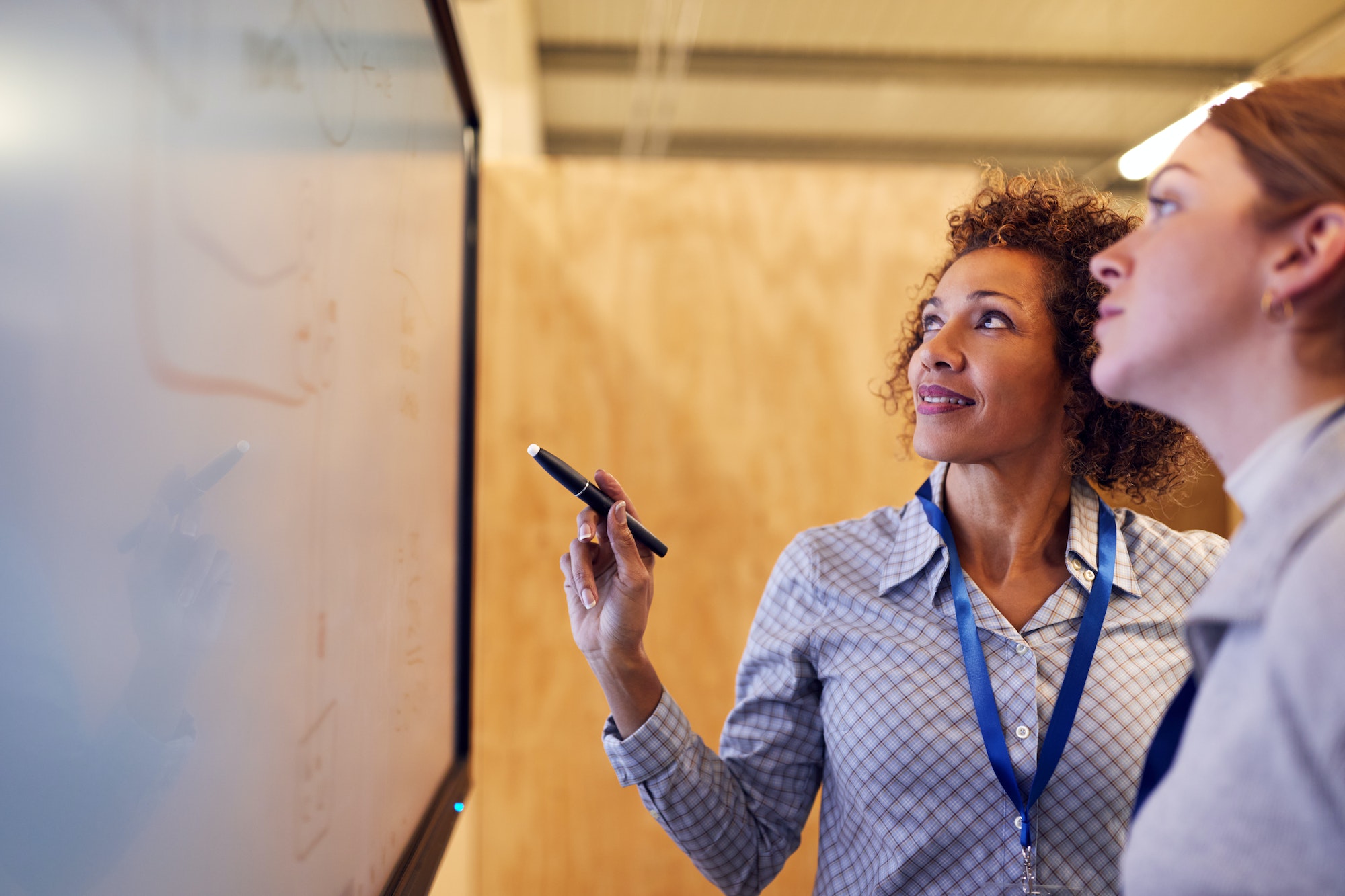 Tutor With Female Trainee Electrician Looking At Wiring Diagram On Screen